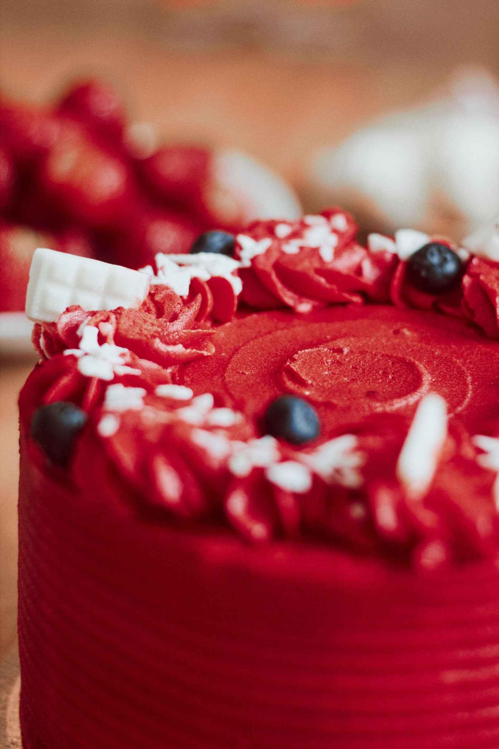 Close-up of a red velvet cake topped with berries and stylish icing, perfect for celebrations.